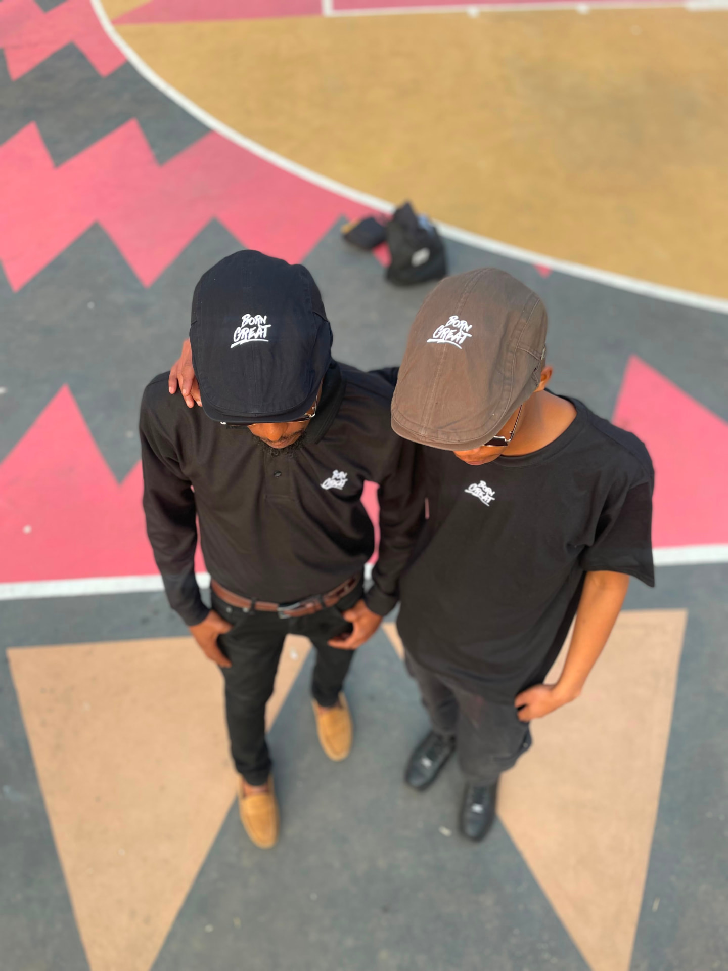 Overhead shot of two men in black Born Great caps and left-chest branding