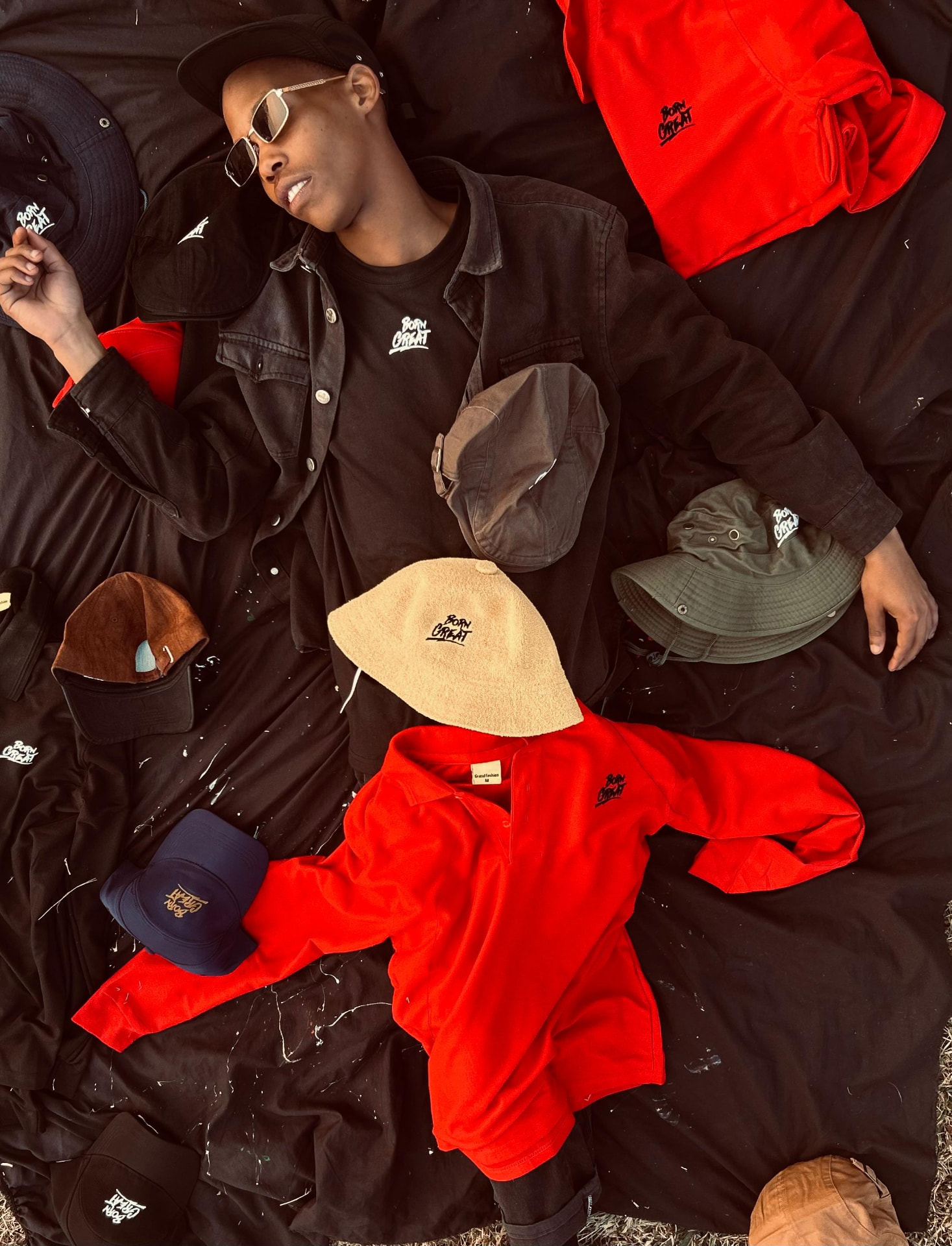 Born Great caps, polos and tees laid out flat